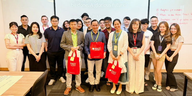 Photo of a lecturer and a group of postgraduate students smiling in front of the class at RMIT Vietnam