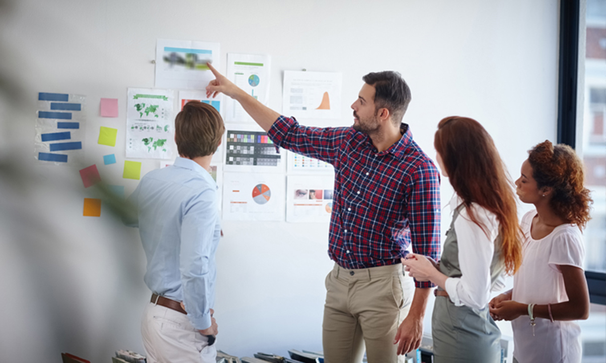 A group of people planning a project with information on the wall